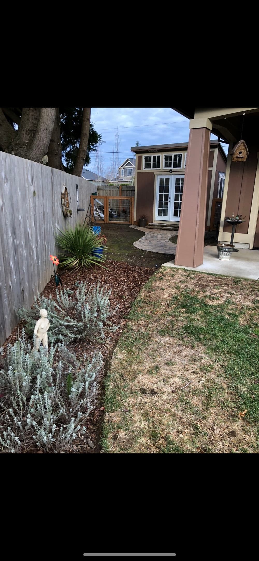 Backyard view featuring landscaped garden, stone path, and decorative statues.