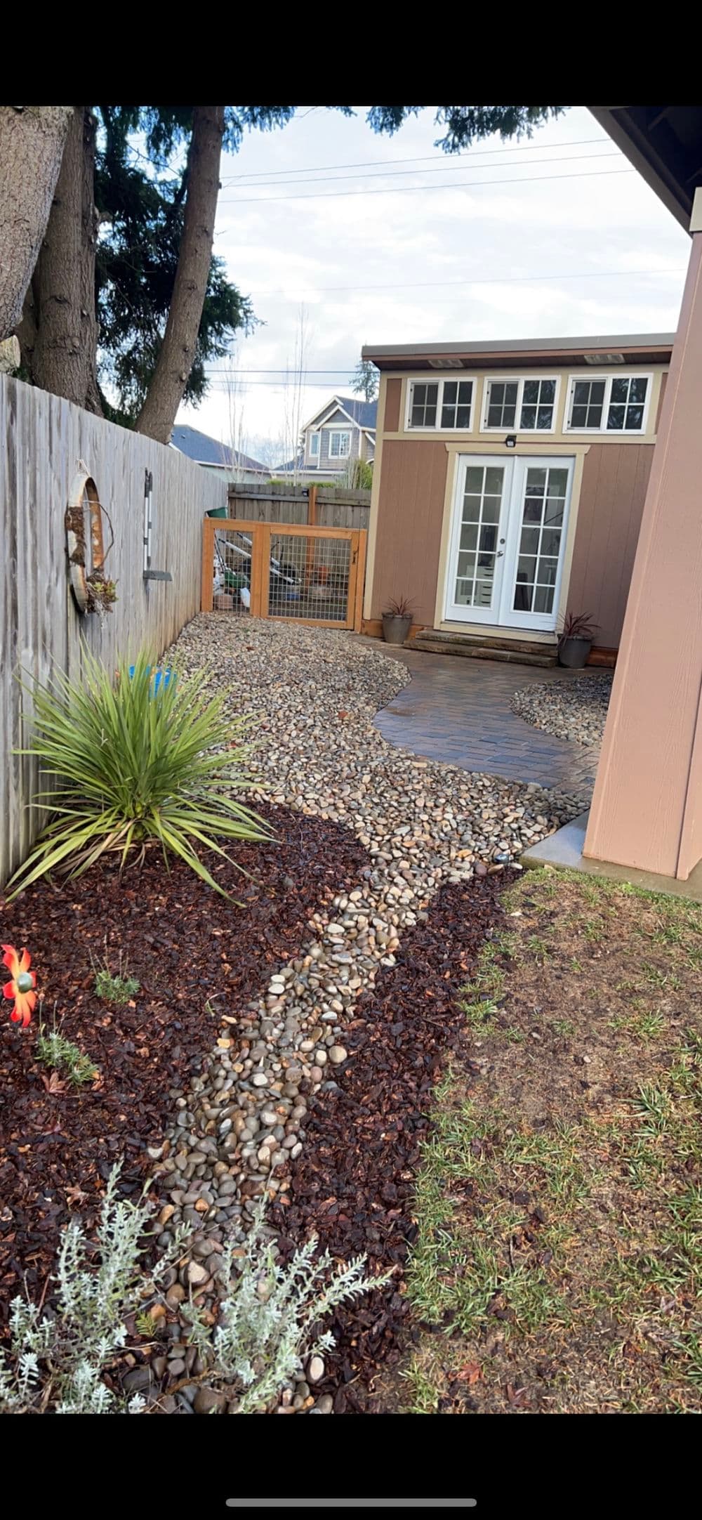 landscaped backyard featuring a stone pathway, decorative plants, and a shed.